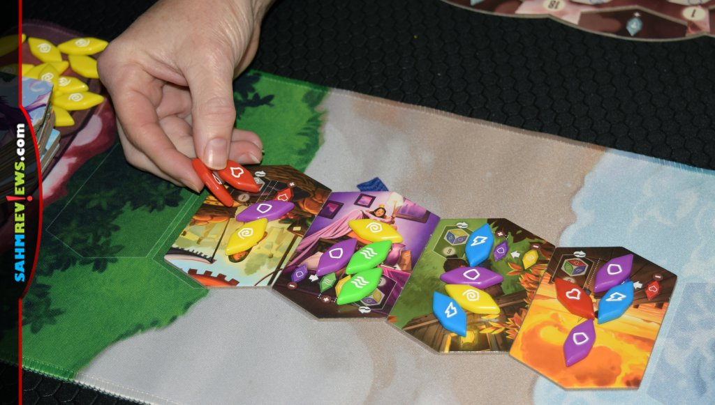 Hand of player selecting fragments from Moment tiles in Vivid Memories board game. - SahmReviews.com