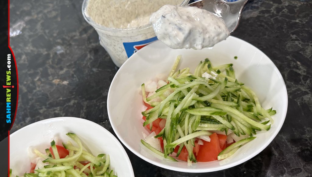 Tzatziki sauce being added to the vegetable mixture for Gyro Salad. - SahmReviews.com