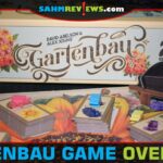 Gartenbau garden-themed tile laying game box behind stacks of seedling tiles and resource wheelbarrows. - SahmReviews.com