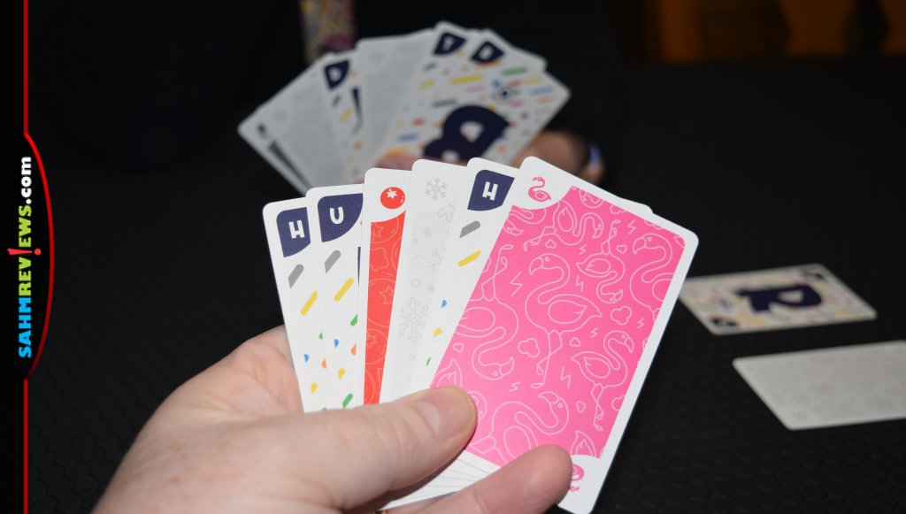 Walkie Talkie hand of cards showing mix of color and letter cards. Background shows back of another player's hand of cards. - SahmReviews.com