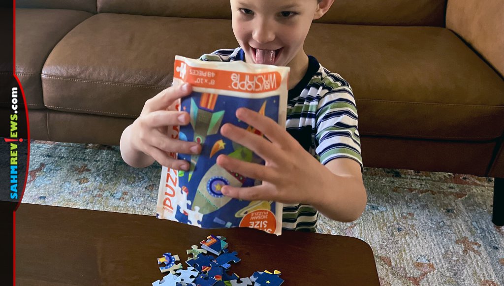 Young boy dumping WerkShoppe 48-piece jigsaw puzzle onto table. - SahmReviews.com