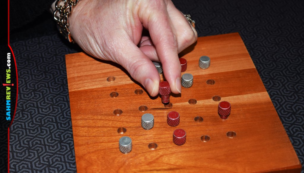 Line 'em Up - A woman's hand moving one of the pieces on the board.